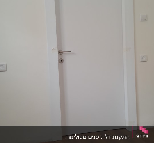 דלת לבנה עם ידית מתכת על רצפת עץ